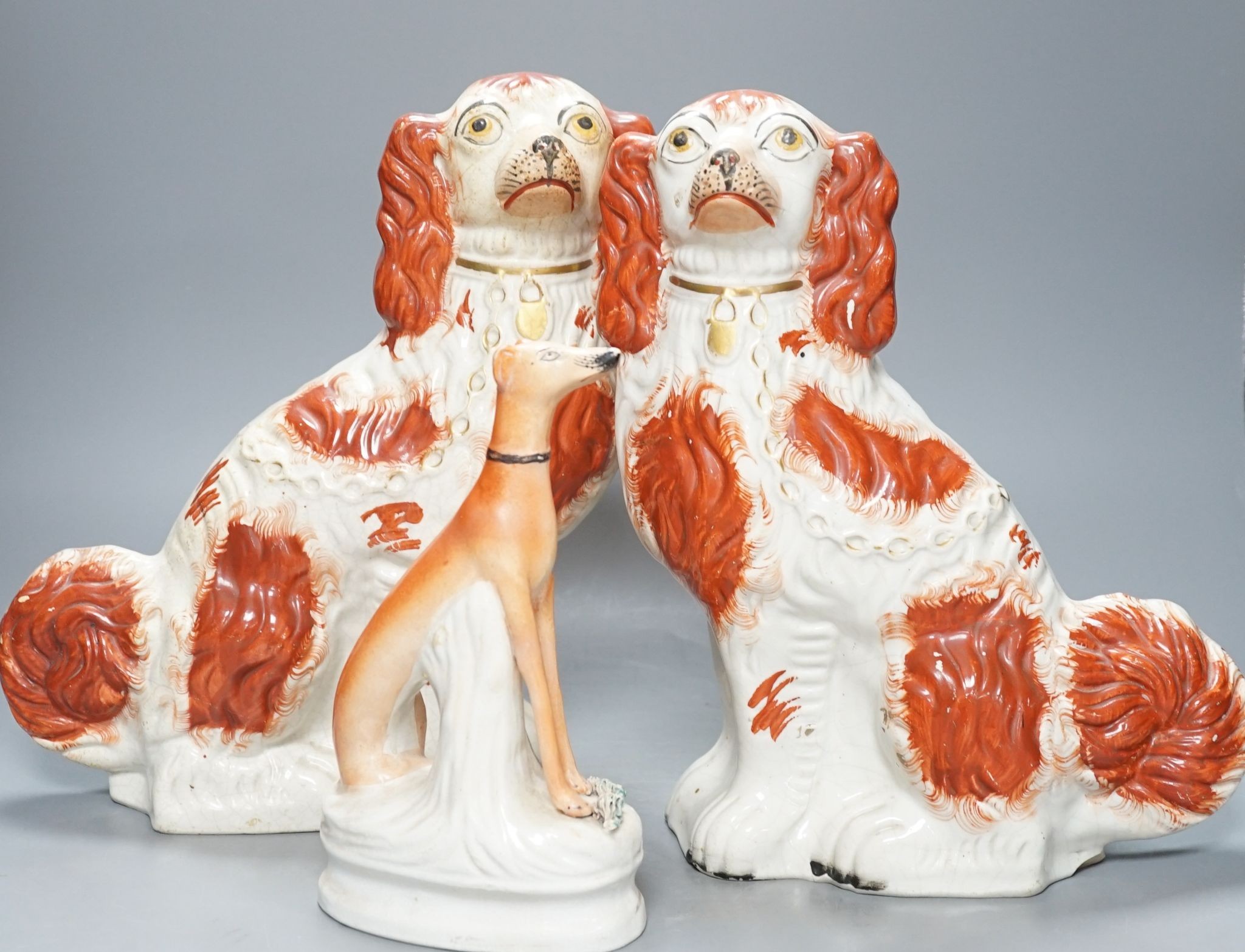 A pair of Victorian Staffordshire Spaniel chimney dogs and a greyhound, chimney dogs 31 cms high.